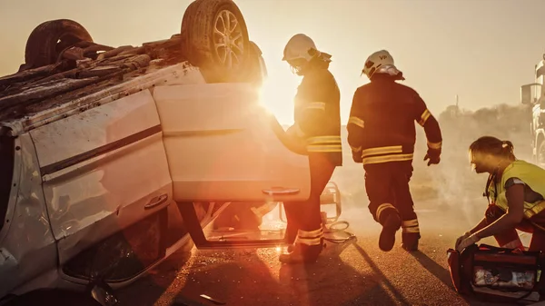 Wypadek samochodowy: ratownicy medyczni i strażacy plan ratowania pasażerów uwięzionych w Rollover Vehicle. Lekarze przygotować nosze i sprzęt pierwszej pomocy. Strażacy używają rozsiewaczy hydraulicznych — Zdjęcie stockowe