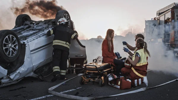 Nehoda při autonehodě: Záchranáři a záchranáři Zachraňte zraněné oběti v pasti. Zdravotníci poskytují první pomoc pasažérce. Hasiči použít hydraulické řezačky rozmetadlo k otevření vozidla — Stock fotografie