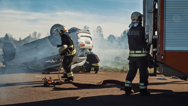 Equipe de resgate de bombeiros chegam ao acidente, catástrofe, local de incêndio em seu motor de incêndio. Bombeiros pegam seus equipamentos, preparam mangueiras de incêndio e engrenagem do caminhão de bombeiros, correm para ajudar pessoas feridas . — Fotografia de Stock