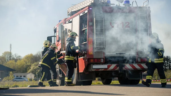 Räddningsteamet av brandmän anländer på bilkraschtrafikplatsen på deras brandbil. Brandmän Ta sina verktyg, Utrustning och, Redskap från brandbil, Rush att hjälpa skadade, Fångade människor — Stockfoto