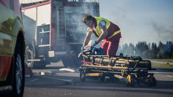 On the Car Crash Traffic Accident Scene: Paramedische Prepairing Stretchers voor het uitvoeren van eerste hulp. Brandweerauto op de achtergrond. — Stockfoto