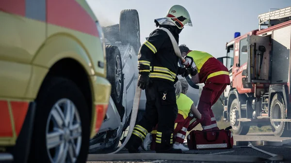 On the Car Crash Traffic Accident Scene: Paramedics and Firefighters Rescue Injured Victims Trapped in the Vehicle. Medics Use Stretchers, Perform First Aid.