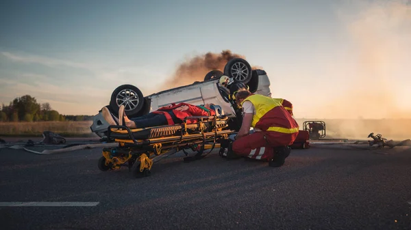 På bilkraschen Trafikolycka Scen: Paramedics Rädda livet på en kvinnlig offer som ligger på bårar. Utför första hjälpen — Stockfoto