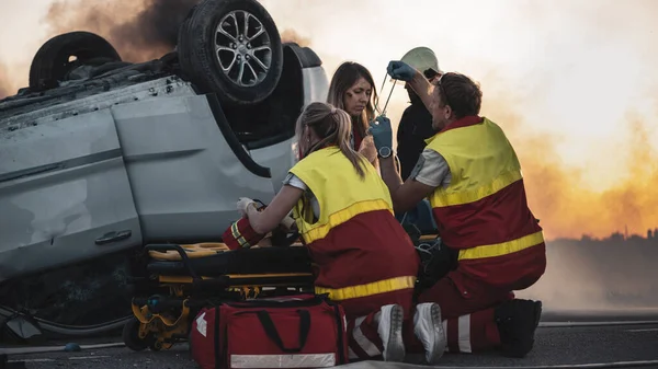 On the Car Crash Traffic Accident Scene: Paramedici EHBO uitvoeren van een vrouwelijk slachtoffer die zit op Stretchers. Ze brengen zuurstofmasker aan.. — Stockfoto