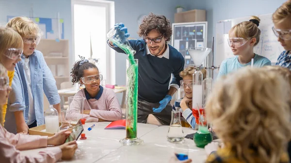 Grundskola vetenskap kemi Klassrum: Lärare visar kemisk reaktion Experiment till grupp av barn. Blandning av kemikalier i bägare för att få reaktionen. Barn Wathcing med intresse. — Stockfoto