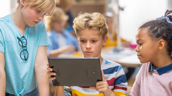 Элементарный школьный урок науки: две девочки и мальчик используют цифровые технологии с повышенной реалистичностью, они возбуждены, полны чудес, любопытства. Дети в STEM, игры, обучение — стоковое фото