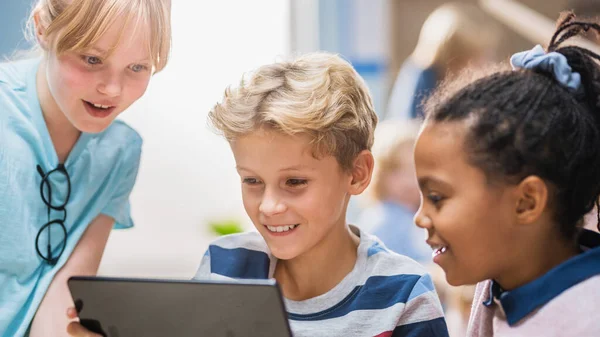 Elementary School Computer Science Class: Two Girls and Boy Use Digital Tablet Computer with Augmented Reality Software, They re Excited, Full of Wonder, Curiosity. Niños en STEM, Jugar, Aprender — Foto de Stock