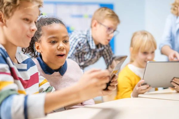 Clase de Ciencias de la Computación de la Escuela Primaria: Los niños usan Tablet Computadoras Digitales y Smartphones con Software de Realidad Aumentada, se vuelven emocionados, llenos de maravillas. Niños en STEM, jugando y aprendiendo — Foto de Stock