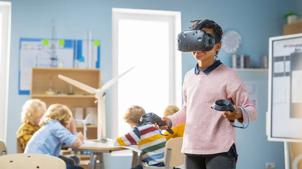 Általános iskola Computer Science Class: Aranyos lány visel kiterjesztett valóság headset és használata vezérlők tanulságok virtuális valóság Izgalmas, kíváncsi és érdekelt a tudás — Stock Fotó