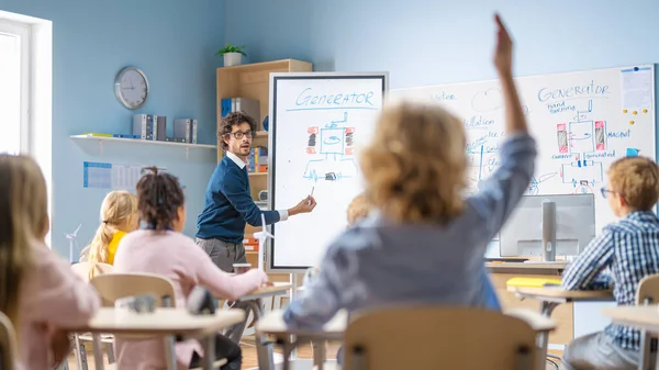 Brillante studente ascolta attentamente il suo insegnante spiegando lezione e alza la mano con una domanda. Nella scuola elementare con il gruppo di bambini multietnici luminosi che imparano la scienza. Colpo alla vista posteriore — Foto Stock