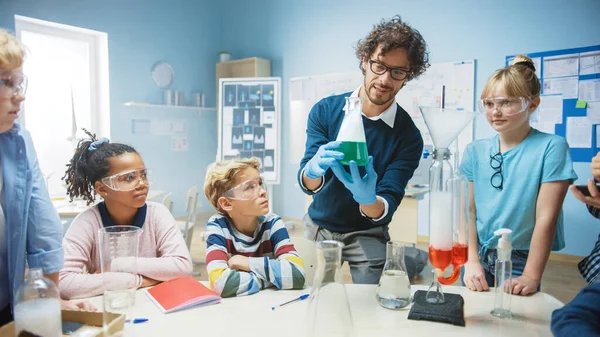 Класс химии начальной школы: Учитель показывает эксперимент химической реакции группе детей. Смешивание химикатов в Бикере, чтобы получить реакцию. Дети используют цифровые планшетные компьютеры — стоковое фото