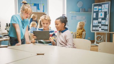 İlköğretim Okulu Bilgisayar Bilimi Sınıfı: İki Kız ve Erkek Artırılmış Gerçeklik Yazılımı ile Dijital Tablet Bilgisayar Kullanıyor, Heyecanlı, Merakla Dolu, Merak Dolu. STEM 'deki Çocuklar, Oynamak, Öğrenmek