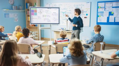 İlköğretim Okulu Bilim Öğretmeni, Yazılım Programının Robotik için nasıl çalıştığını göstermek için İnteraktif Dijital Whiteboard kullanıyor. Bilim sınıfı, meraklı çocuklar özenle dinliyorlar.