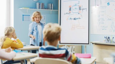 İlköğretim Okulu Bilim Sınıfı: Şirin Genç Öğrenci, Sınıf arkadaşlarıyla dolu bir sınıfa yenilenebilir enerjinin nasıl çalıştığını göstermek için etkileşimli dijital beyaz tahta kullanıyor. Fen dersi, Meraklı Çocuklar Dinliyor