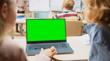 İlköğretim Okulu Bilim Sınıfı: Omuz Ufaklığı ve Kız Yeşil Ekran Model Şablonu ile Laptop Kullanıyor. Fizik öğretmeni, zeki çocuklarla dolu çeşitli sınıflara ders veriyor.