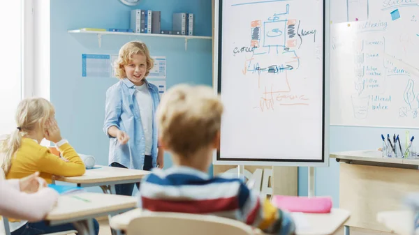 초등 학교 과학 클래스 : Cute Young Student Uses Interactive Digital Whiteboard to Show to a Classroom full of Classmates how Renewable Energy works. 과학 시간에 귀를 기울이는 호기심많은 아이들 — 스톡 사진