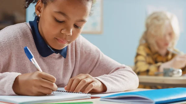 İlköğretim Okulu 'nda Zeki Siyah Kız, Egzersiz Defteri Yazıyor, Sınav ve Yazma Sınavı Yapıyor. Bir grup Parlak Çocuk Özenle Çalışıyor ve Yeni Şeyler Öğreniyor — Stok fotoğraf