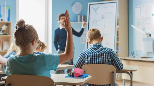 Briljante Schoolmeisje heft de hand met een antwoord. Op de basisschool met een groep van Bright Multiethnic Kids Learning Science. Achteraanzicht neergeschoten — Stockfoto