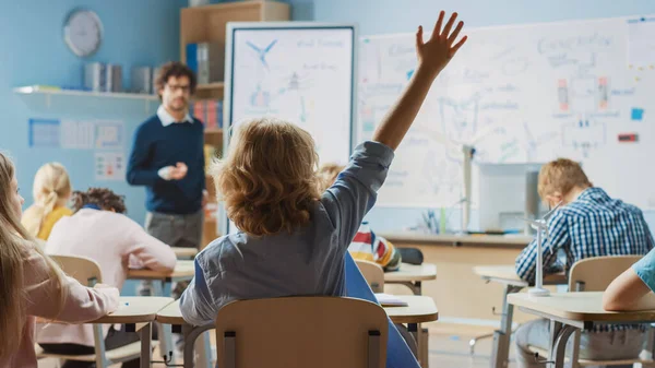 Brillanter Schuljunge hört aufmerksam zu, wie sein Lehrer die Lektion erklärt. In der Grundschule mit einer Gruppe heller multiethnischer Kinder, die Naturwissenschaften lernen. Kamerafahrt mit Fokus auf Schüler — Stockfoto