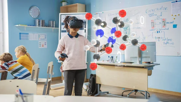 Linda chica que usa auriculares de realidad aumentada y el uso de controladores interactúa con la molécula 3D. Clase de Ciencias Escolares Futurísticas para el Aprendizaje Infantil en Programas STEM. VFX, renderizado de efectos especiales —  Fotos de Stock