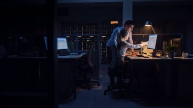 Hırslı İşadamı Masaüstü Bilgisayarını Kullanıyor, Onun Kadın Proje Yöneticisi Özel Görevleri, Hesaplama ve Stratejik Hareketleri Açıklıyor. Büyük Şirket Ofisinde Profesyonel İnsanlar Geceleyin Geç Saatlere Kadar Çalışıyor