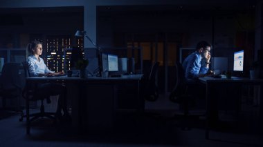 Ofiste Geç Saatlere Kadar Çalışmak: İş Adamları Masaüstü Bilgisayarı Kullanıyor, Analiz Ediyor, Belgeleri Kullanıyor, Sorunları Çözüyor, Önemli Projeyi Bitiyor. Yan Görünüm