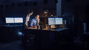 Hırslı, kendinden emin işadamı, Masaüstü Bilgisayarı kullanıyor, Kadın Proje Yöneticisi, Özel Görevleri, Hesaplama ve Stratejik Hareketleri Açıklıyor. Profesyonel İnsanlar Şirket Ofisinde Gece Geç Saatlere Kadar Çalışıyor