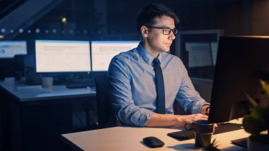 Hırslı ve kendinden emin iş adamının portresi Masaüstü Bilgisayarı kullanıyor, Bir Klavyede Yazıyor, Ticari İşlemleri İzliyor, Sözleşmeleri İmzalıyor. Büyük Şirket Ofisinde Gece Geç Saatlere Kadar Çalışıyor