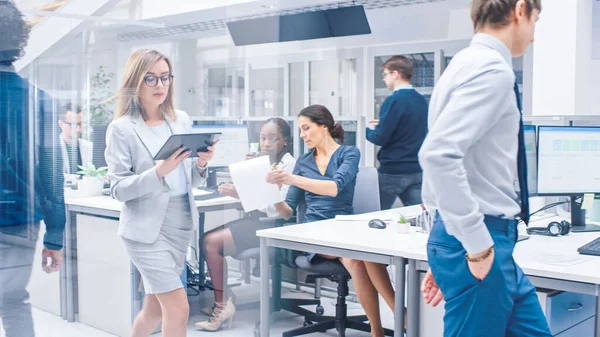 In den prall gefüllten Büroreihen arbeiten junge Fachkräfte an Desktop-Computern, sprechen, betreuen Kunden, kommunizieren mit Kunden, überwachen Statistiken, gehen durch Flure — Stockfoto