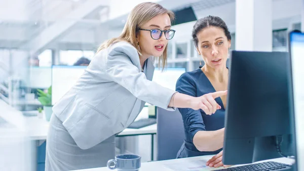 In the Busy Corporate Office: Female Manager vysvětluje úkol podnikatelce, která pracuje na stolním počítači. Podnikatelé pracují s klienty, diskutují a analyzují statistiky — Stock fotografie