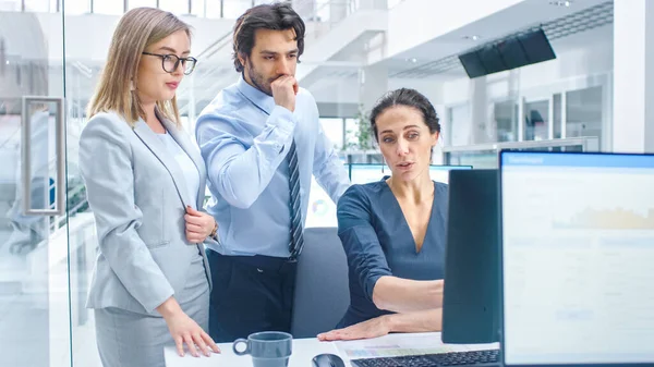 Im hellen modernen Büro: Büroangestellte sitzt und arbeitet an ihrem Desktop-Computer und diskutiert mit ihrem Projektleiter und Teamleiter über Problemlösungen. Jungunternehmer planen und lösen Probleme — Stockfoto