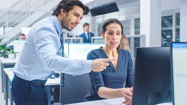 Dans le bureau corporatif occupé : Femme gestionnaire explique tâche à Businesswoman qui travaille sur ordinateur de bureau. Les entreprises et le travail avec les clients, les discussions et l'analyse des statistiques — Photo