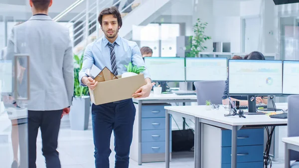 Sad Fired Let Go Office Worker Packs His Belongings into Cardboard Box and Leaves Office. Workforce Reduction, Downsizing, Reorganization, Restructuring, Outsourcing. Mass Unemployment Market Crisis