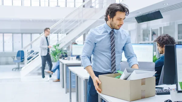 Sad Fired Let Go Office Worker Packs His Belongings into Cardboard Box and Leaves Office. Workforce Reduction, Downsizing, Reorganization, Restructuring, Outsourcing. Mass Unemployment Market Crisis