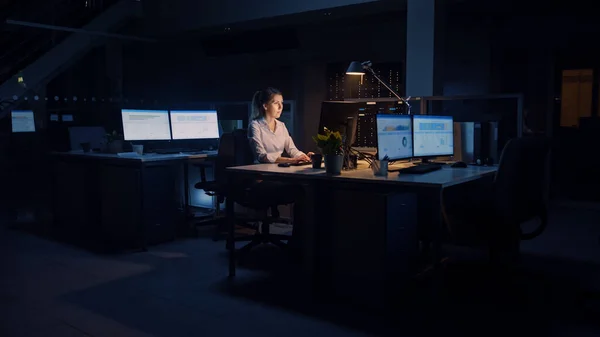 办公室工作到深夜：女商人使用台式计算机、分析、使用文件、解决问题、完成重要项目。勤勉的有抱负的青年工人 — 图库照片