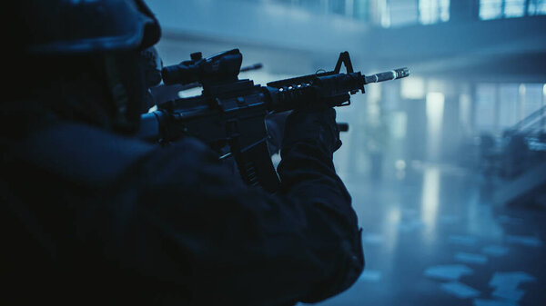 Close Up Portrait of Masked Armed SWAT Police Officer Storming Dark Seized Office Building with Desks and Computers. Soldiers with Rifles and Flashlights Move Forward and Cover Surroundings.