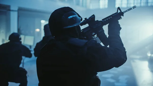 Porträtt av maskerad beväpnad SWAT-polis Storming Dark Seized Office Building med skrivbord och datorer. Soldater med gevär och ficklampor rör sig framåt och täcka omgivningar. — Stockfoto