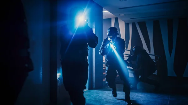 Silahlı SWAT ekipleri asansörden çıkın ve bir ofis binasının koridoruna hücum edin. Tüfekli ve fenerli askerler İlerleyin ve etraflarını sarın.. — Stok fotoğraf