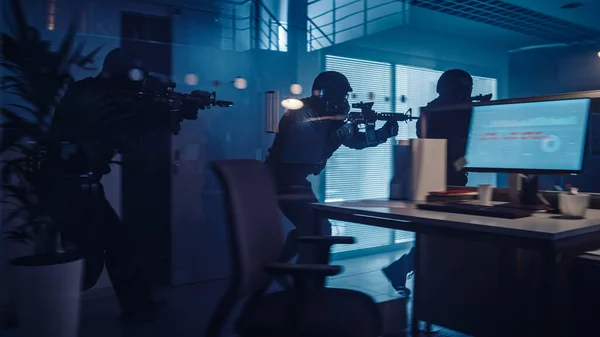 Masked Squad of Armed SWAT police police officers move in a Hall of a Dark Seized Office Building with Desks and Computers. 경찰, 데스크와 컴퓨터로 움직이다. 지렛대와 섬광등을 가지고 있는 군인들의 수면 덮개와 수면 위를 덮고 있다. — 스톡 사진