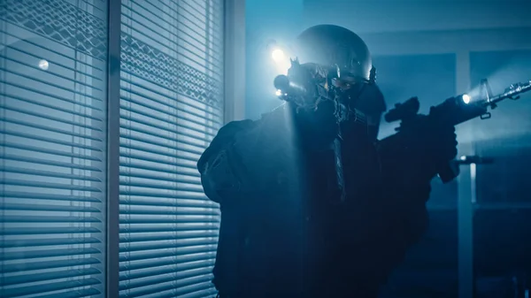 Närbild Porträtt av maskerad beväpnad SWAT polis Storm en mörk beslagtagen kontorsbyggnad med skrivbord och datorer. Soldater med gevär och ficklampor rör sig framåt och täcka omgivningar. — Stockfoto