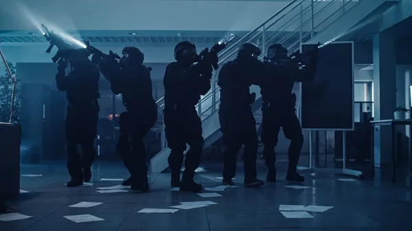 Maskovaný tým ozbrojených policistů SWAT Pohybují se v hale temně obsazené kancelářské budovy se stoly a počítači. Vojáci s puškami a baterkami Průzkum a obal. — Stock fotografie