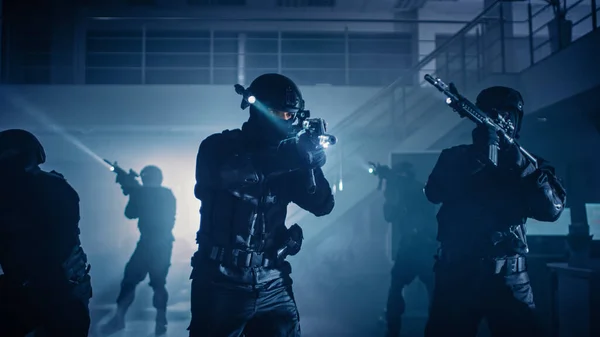 Maskované komando ozbrojených policistů SWAT stojí v temně obsazené kancelářské budově se stoly a počítači. Vojáci s puškami a baterkami Průzkum a obal. — Stock fotografie