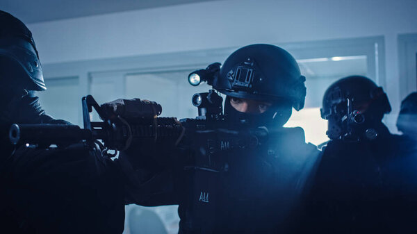 Close Up Portraits of Masked Squad of Armed SWAT Police Officers Storm a Dark Seized Office Building with Desks and Computers. Soldiers with Rifles and Flashlights Move Forward and Cover Surroundings.