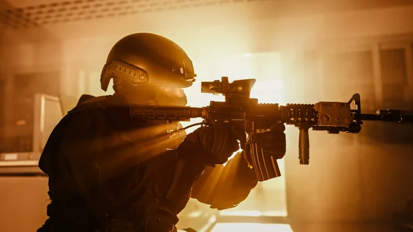 Close Up Retrato de Esquadrão Mascarado Membro de Policiais da SWAT Armados que invadem um prédio de escritórios com mesas e computadores. Soldados com espingardas e lanternas. Classificação de cores quentes. — Fotografia de Stock