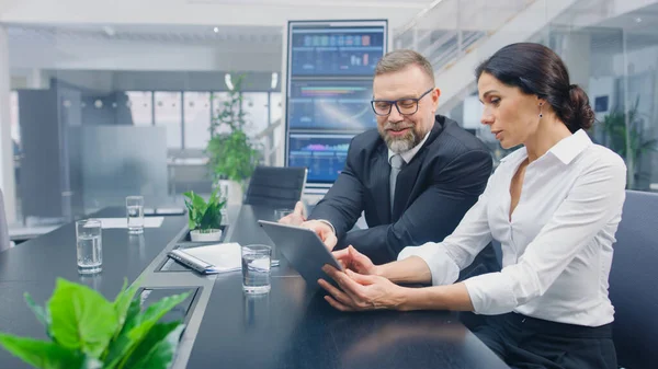 Dans la salle de réunion, des femmes exécutives montrent une tablette numérique à un investisseur masculin, elles discutent des statistiques et du potentiel d'investissement en capital de risque. Bureau d'entreprise occupé avec des hommes d'affaires travaillant — Photo