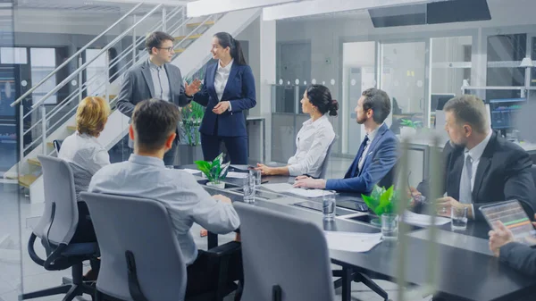 In Corporate Office Meeting Room: Two Young Company Re-Branding Strategists and Trend Growth Development Specialists Deliver Inspiring Speech to a Board of Directors Sitting at Conference Table — Stock Photo, Image