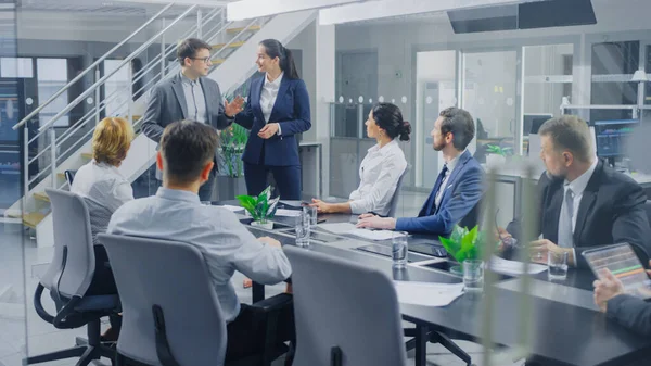 A Vállalati Iroda tárgyalótermében: Két Fiatal Vállalat Re-Branding Strategists and Trend Growth Development Specialists Inspiring Speech to a Board of Directors Sitting at Conference Table — Stock Fotó