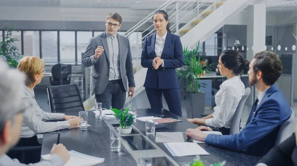 Dans la salle de réunion du bureau corporatif : Deux jeunes stratèges en redéfinition de l'image de marque et spécialistes du développement des tendances prononcent un discours inspirant devant un conseil d'administration assis à la table de conférence — Photo