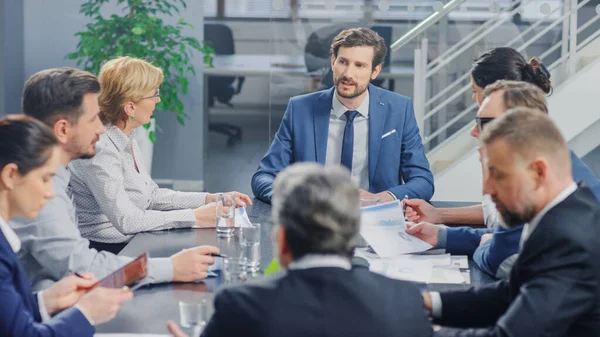 I det moderne Bedriftskontorets møterom: Diverse gruppe av forretningsfolk, advokater, ledere og medlemmer av styret som snakker, forhandler, bruker dokumenter og konsulterer statistiske grafer – stockfoto