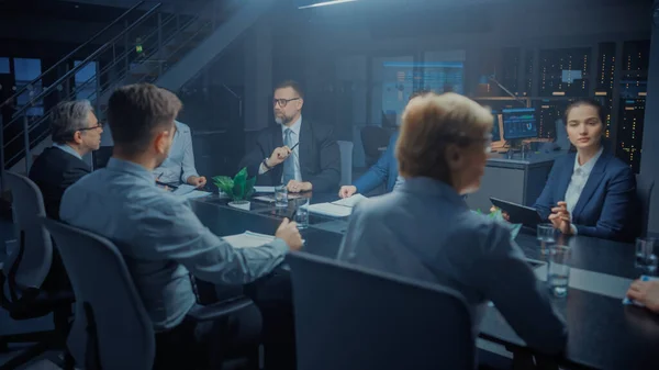 In the Modern Corporate Meeting Room: Diverse Group of Businesspeople, Lawyers, Executives and Directors Talking, Negotiating, Working with Documents, Planning Strategy. Late at Night in the Office